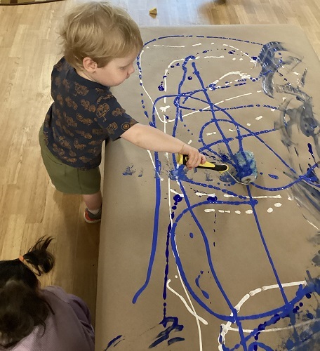 Toddler using different tools to paint with