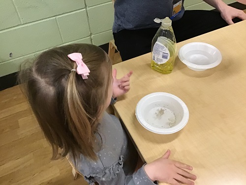 A child sitting at a table with a bowl of water in front of her