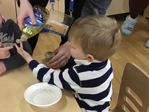 An educator putting a bit of dish soap on a child's finger