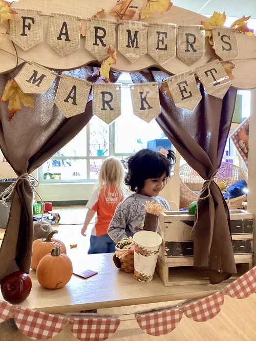 A preschool child playing in their farmers market