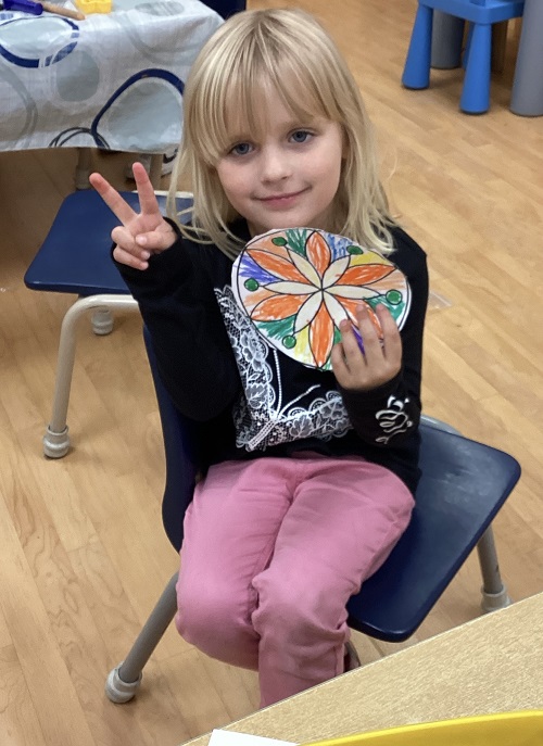 Child displaying her Rangoli art work