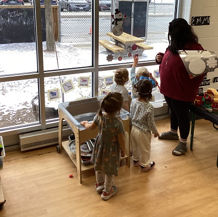 educator standing at window with children
