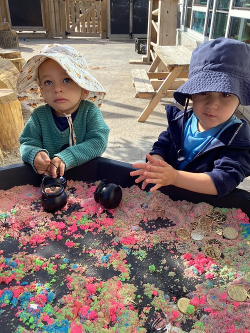 Preschool children working with colourful sand in the tuff tray
