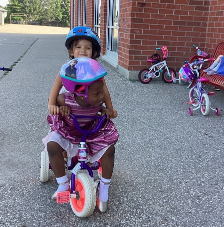 two children on a pink and purple tricycle