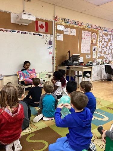 Child presenting book about Holi to group