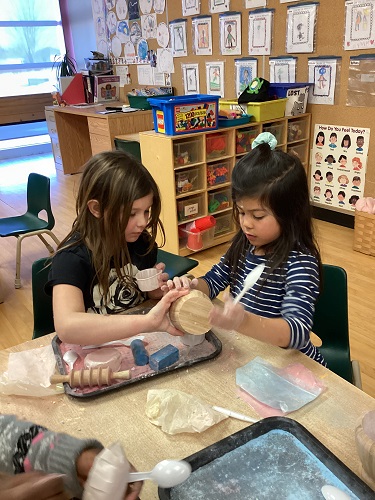 Two school-age girls working together to crush chalk