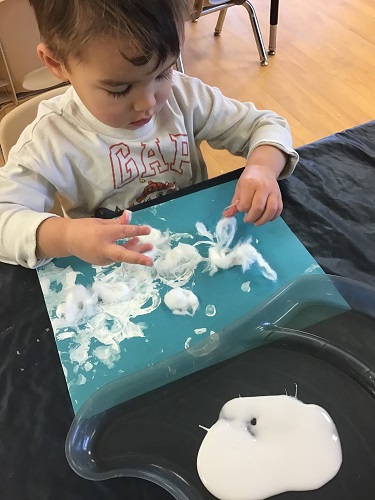 Toddler boy stretching cotton balls