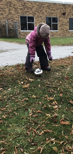 A child rolling a wheel down a small hill