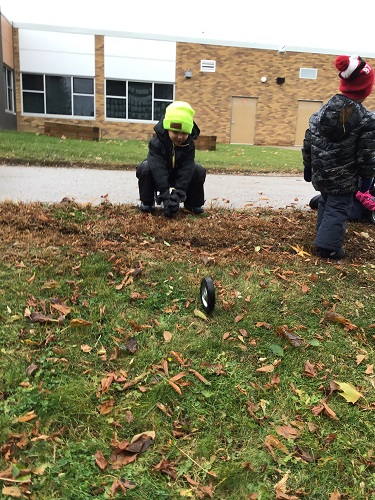 A child rolling a wheel down a small hill