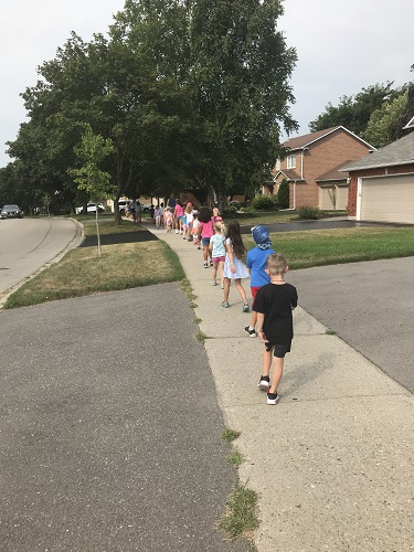 A group of children walking in a line down the sidewalk
