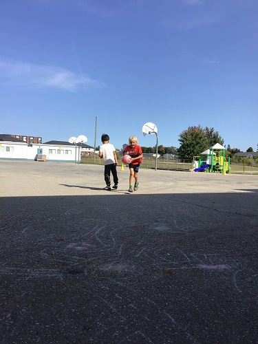 Two children on the blacktop playing with a basketball