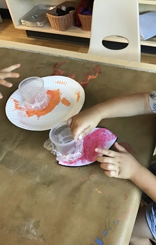 A child at a table painting a leaf