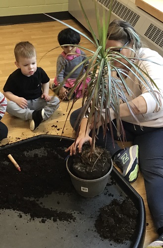 An educator and children looking at the roots of a plant