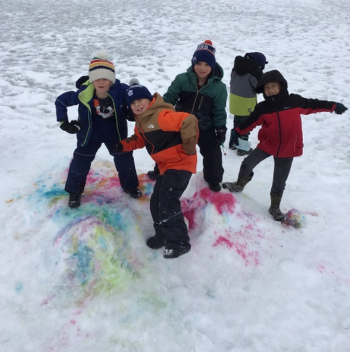 Children standing on top of painted snow posing for the camera