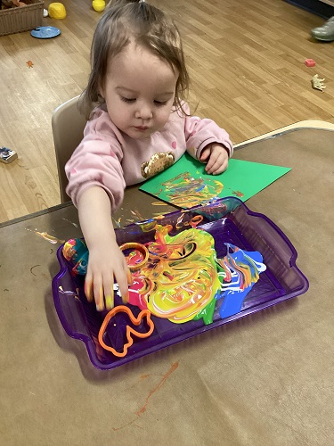A child decorating a construction paper kite at a table