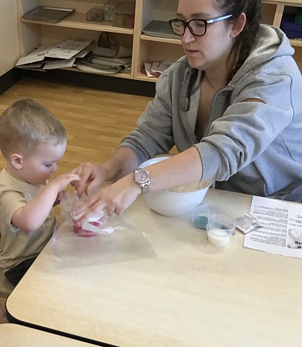 A child helping an educator scoop ingredients into a bag