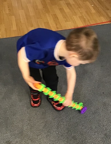 A child holding a creation made out of gears, pretending it is a vacuum