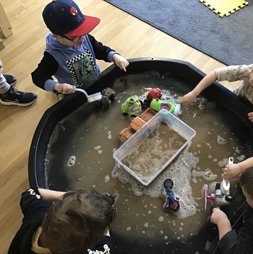 Children washing cars off in the Tuff Tray
