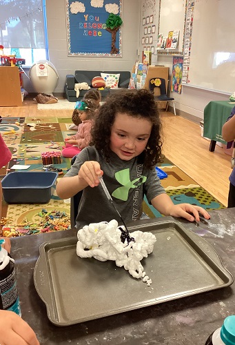 A child adding food colouring to shaving cream