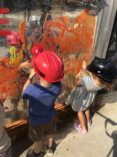 Children spraying paint off a mirror with water