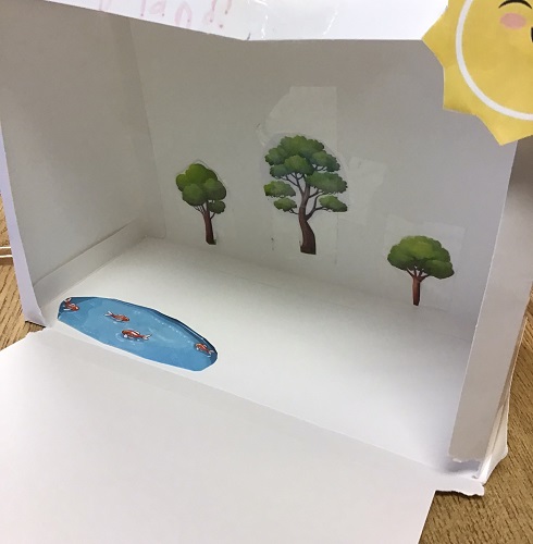 Paper ecosystem with trees, a pond and a sun