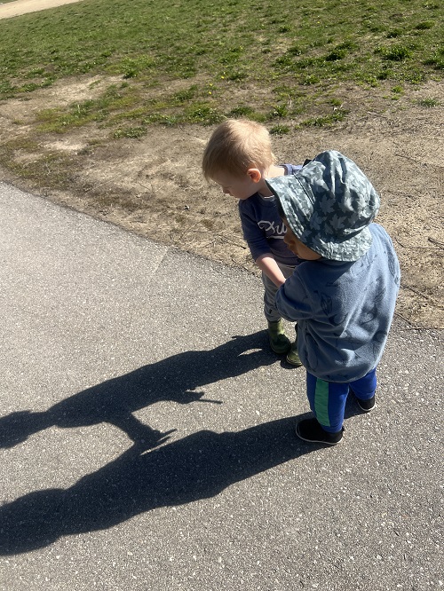 2 toddler children exploring their shadows