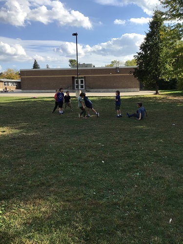 7 school age children standing around together facing each other