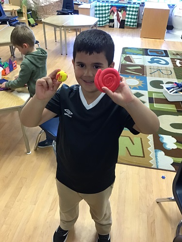 A child holding up his clay creations