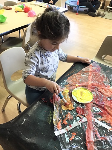 Child painting fall colours on big leaf