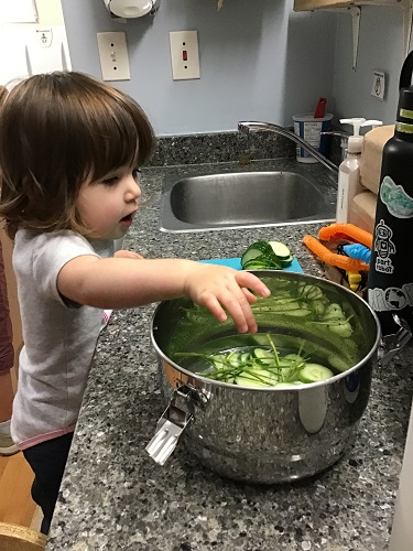 child reaching for the pickles