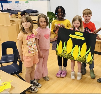 A group of school age children proudly displaying their art project