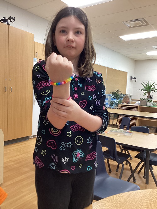 A school age child showing off a bracelet