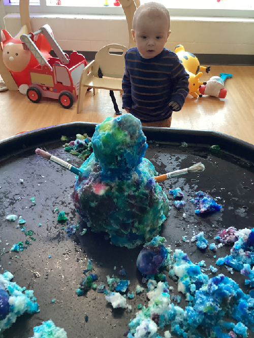 A child observing the snow sculpture in the tuff tray