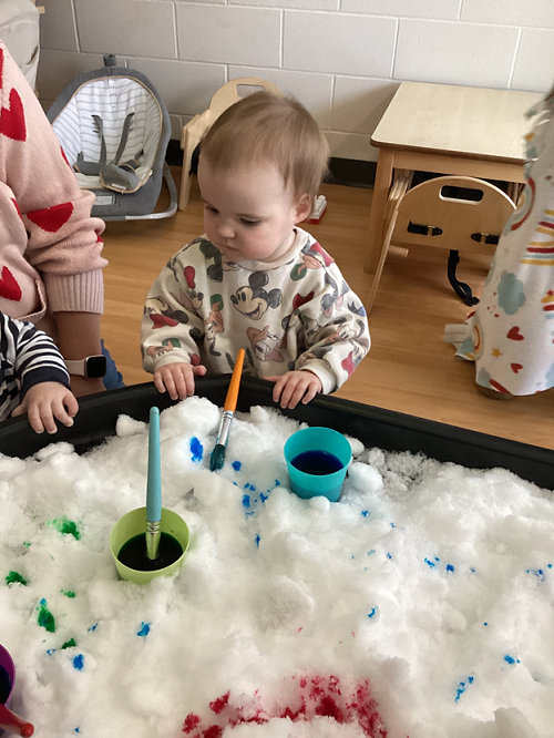 A child observing the snow in the tuff tray