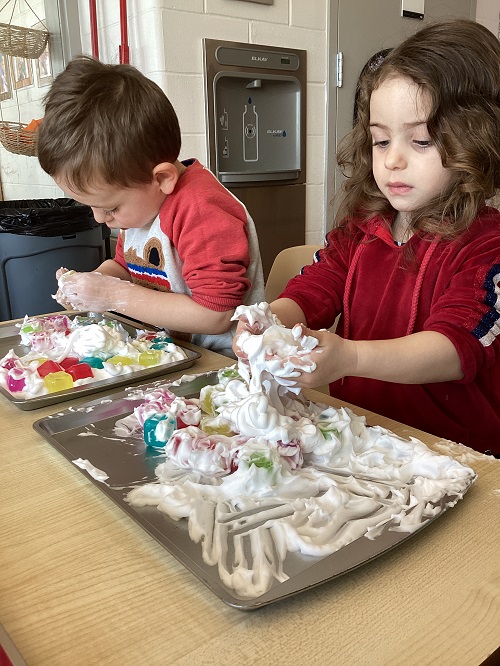Two children exploring with shave foam and loose parts.