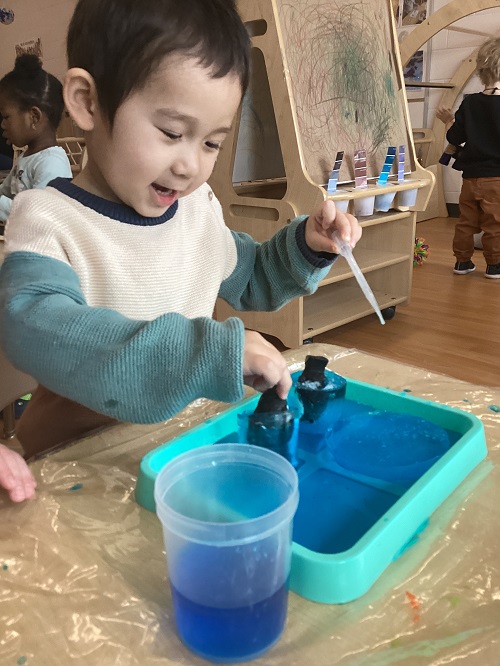 A child using a water dropper on their frozen treasure