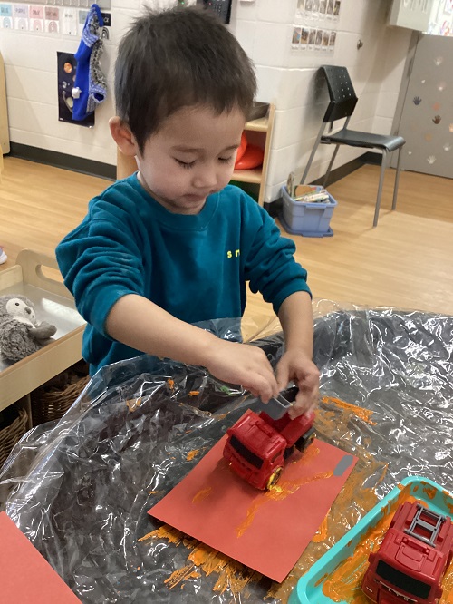 A child using a firetruck as a paintbrush.