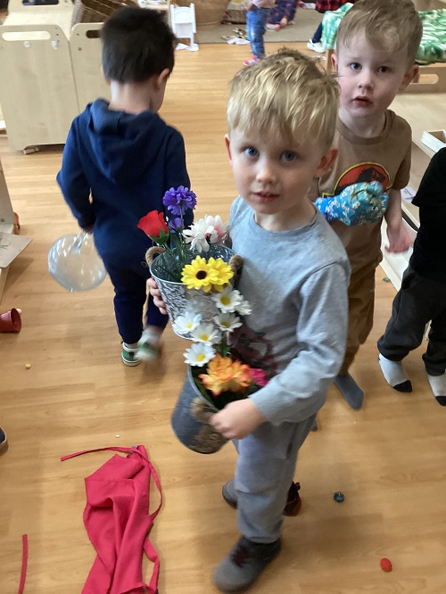 A child holding a floral arrangement they created.