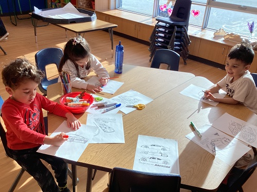 A small group of children drawing and colouring cars.