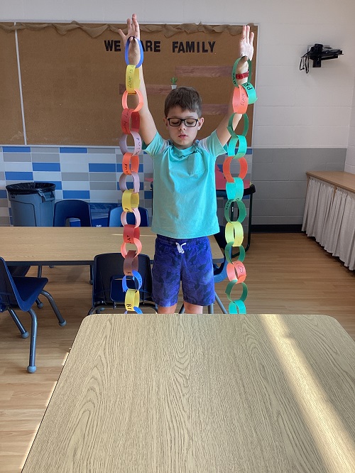 A child holding up a rainbow chain they helped create.