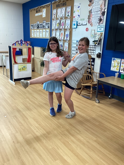 Two children engaging in dance in the classroom.