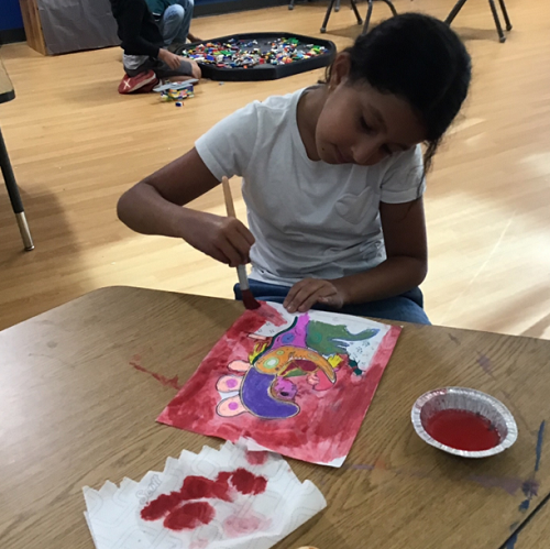 A school age child engaging in some Norval Morrisseau inspired art