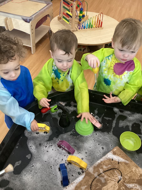 A small group of children exploring with vehicles while washing them
