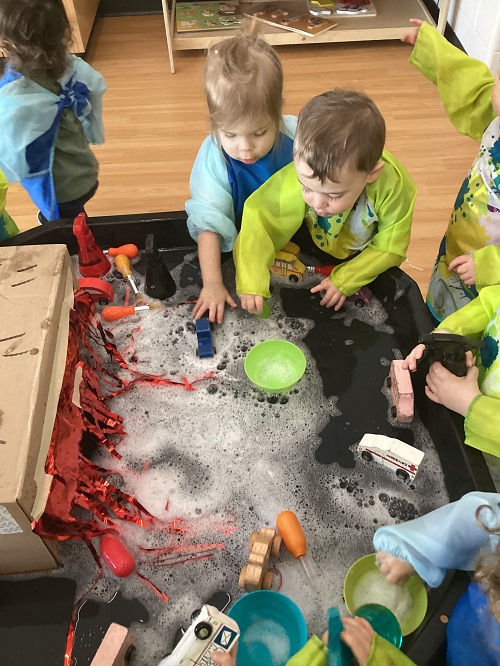 A small group of children exploring with vehicles while washing them