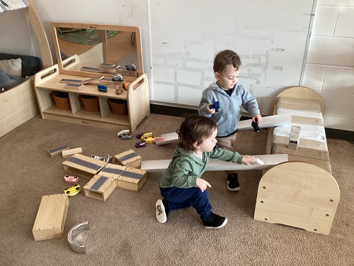 Two children driving their cars on the ramps they created.