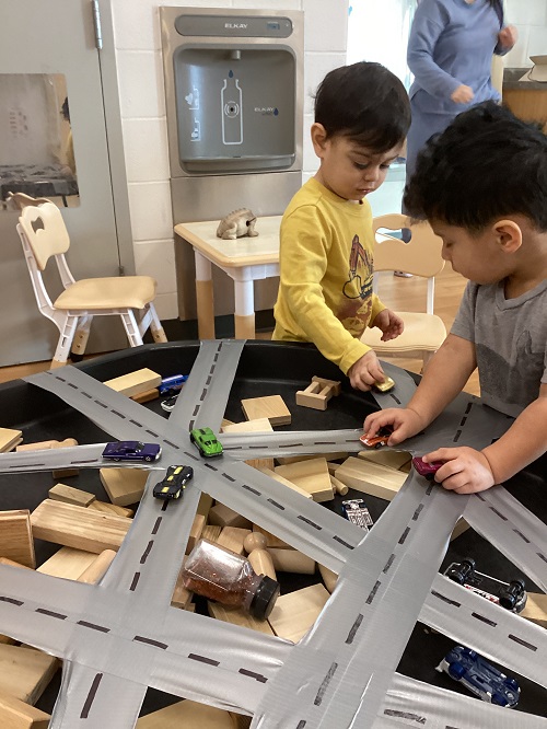 Two children exploring with vehicles and a track