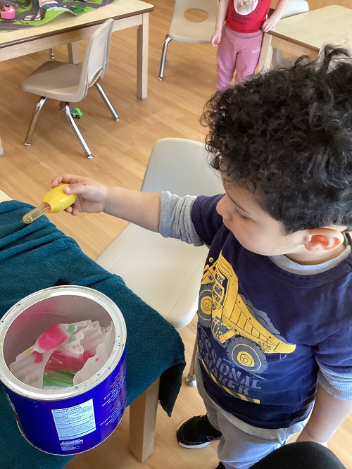 A child using a water-dropper to drip coloured water onto coffee filters.