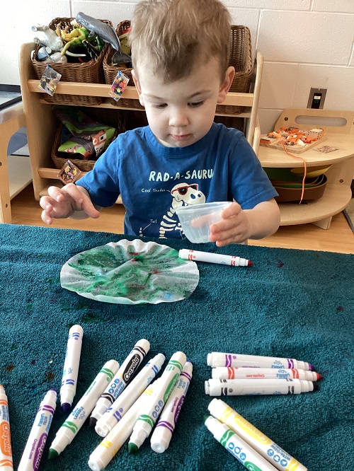 A child using a marker to dye a coffee filter.