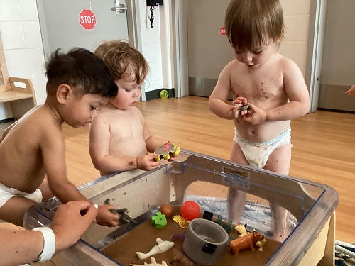 A small group of children exploring the farm-themed sensory bin.