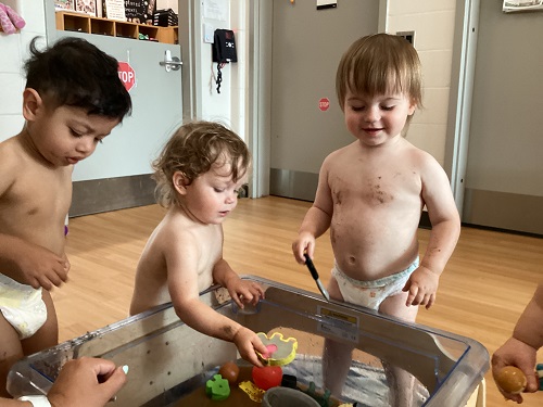 A small group of children exploring the farm-themed sensory bin.